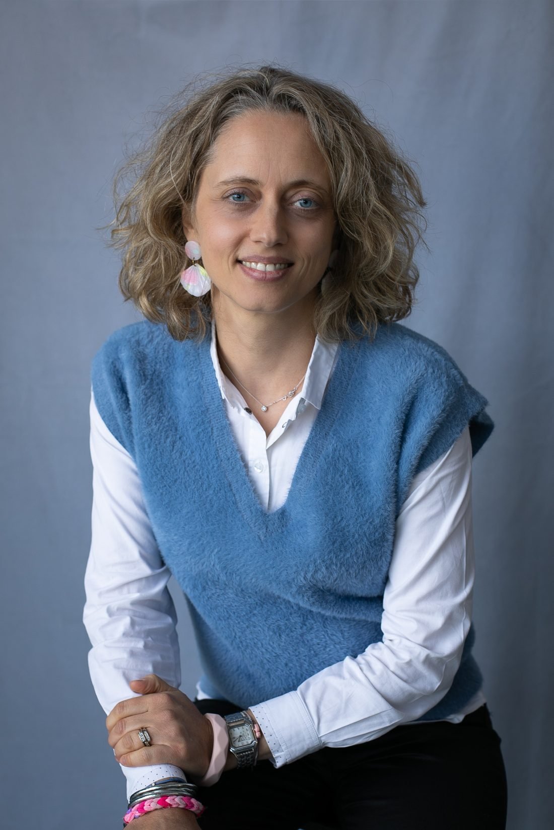 Portrait de Mariel Muller, souriante, pull bleu sur chemise blanche